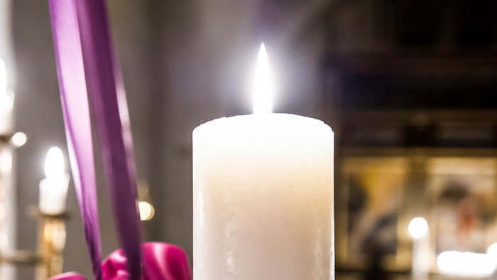 En lysende lyse med lilla bånd og gran.