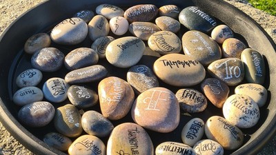 En sort bowl med sten med skriverier på.