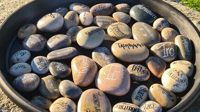 En sort bowl med sten med skriverier på.