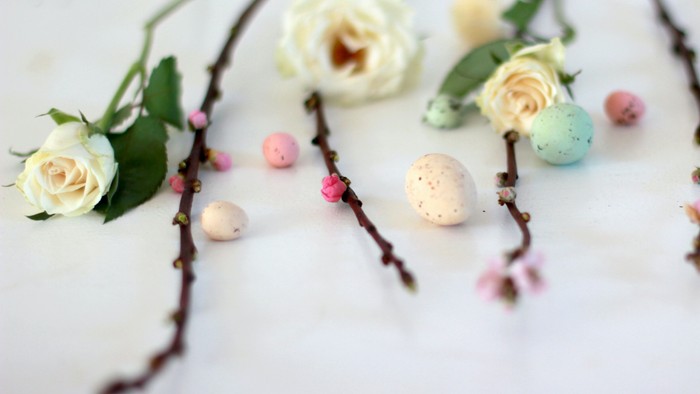 Weiße Rosen und bunte Ostereier auf weißem Hintergrund