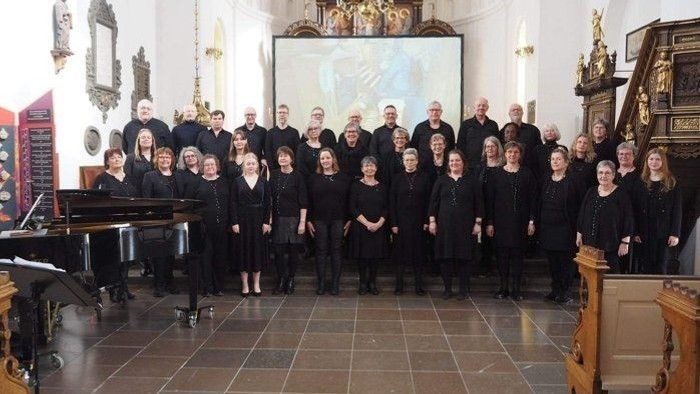 En korgruppe poserer i kirke med piano og orgel.