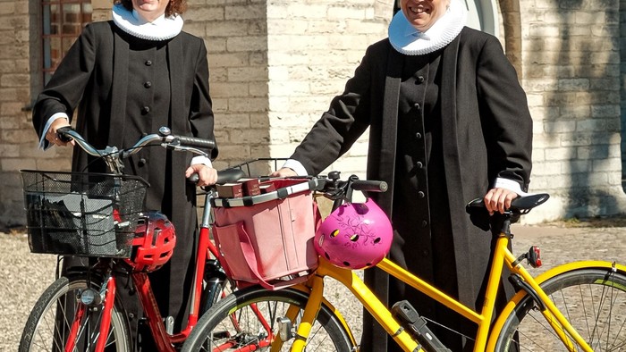 To nonner på cykler foran murstensbygning