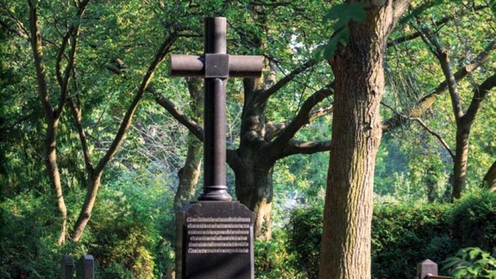 Ein Grabstein mit Kreuz in einem grünen Park