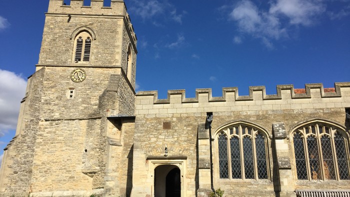 Stone church with tower and arched doorway under blue sky