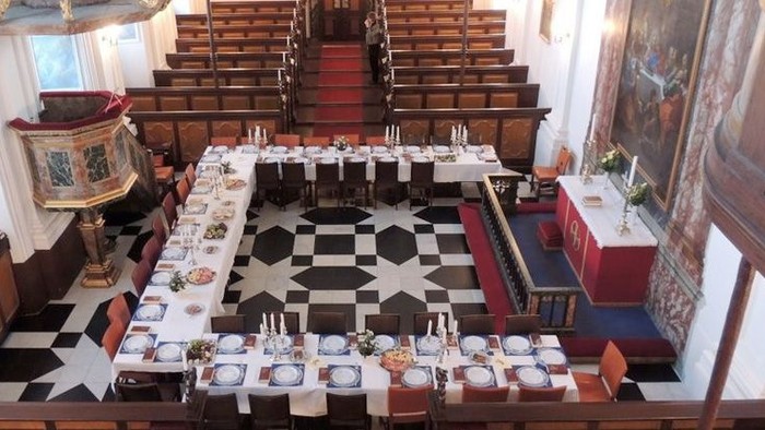 Stor spisesal med sorte og hvide tæpper og mange bord med stilleben.