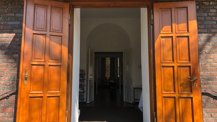 Zwei offene Holztüren vor einem Gebäude