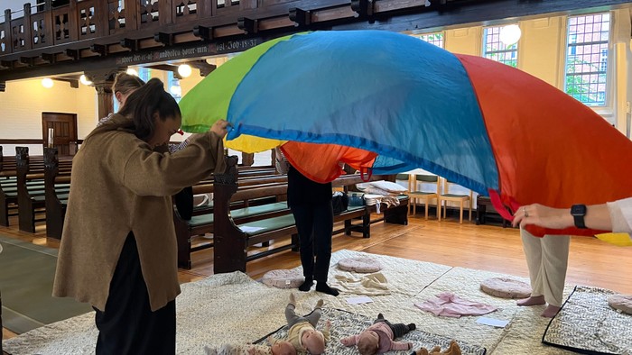 Mennesker i en kirke arrangerer farverige paraplyer og konkylier på et bord.