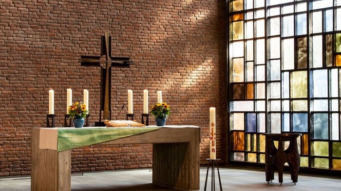 Ein Kirchenaltar vor einem Ziegelsteinwall und buntem Glasfenster