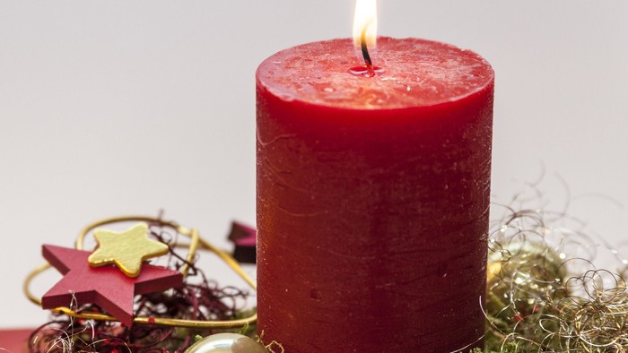 En rød lysende lyse med juledekorationen omkring