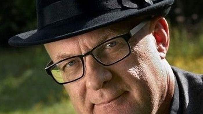 En ældre mand med briller og fedora.