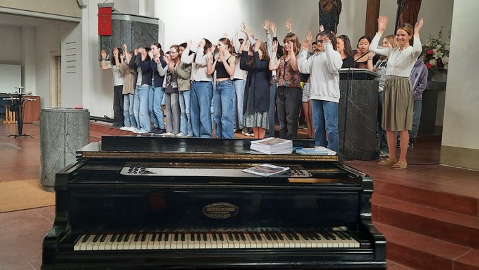 Ein Chor singt in einer Kirche vor einem Klavier
