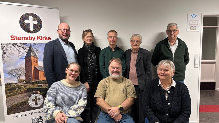 Gruppe af mennesker, der poser sammen foran et banner