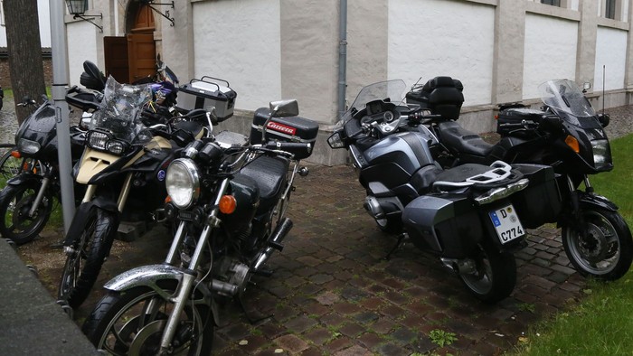 Drei Motorräder sind vor einem weißen Gebäude geparkt.
