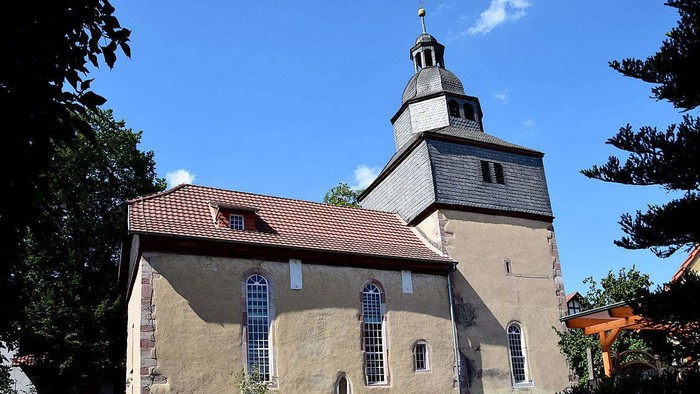 Kirchengebäude mit hohem Turm und rotem Dach unter blauem Himmel