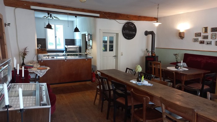 Gemütliches Restaurant mit Holztischen und Stühlen, offener Küche und Barhockern