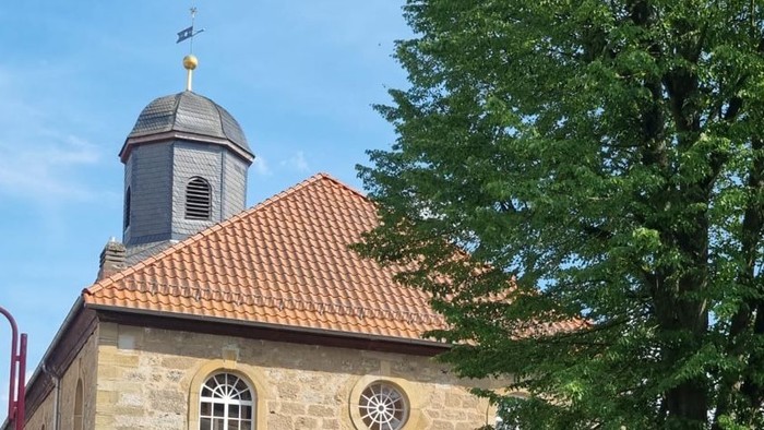 Kleine Kirche mit rotem Dach und grünem Rasen davor