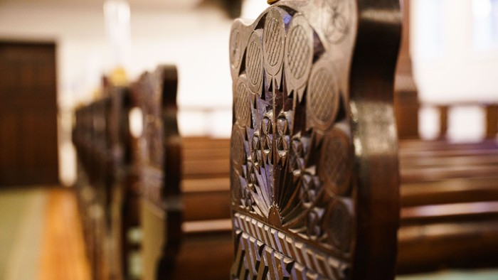 Indviklede trækirkebænke med udskårne ørne- og blomstermotiver på ryglænene.