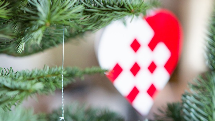 En skinnende rød julekugle hænger på en gren.