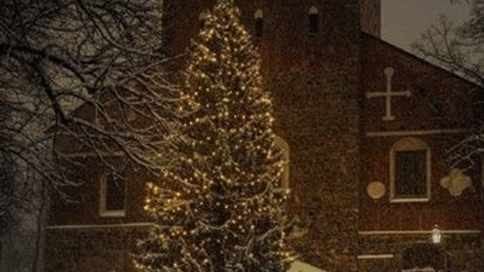 En juletree foran kirke med lys og stjerner