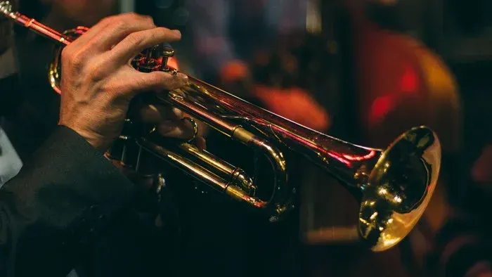 Eine Hand spielt eine goldene Trompete in einem dunklen Raum.