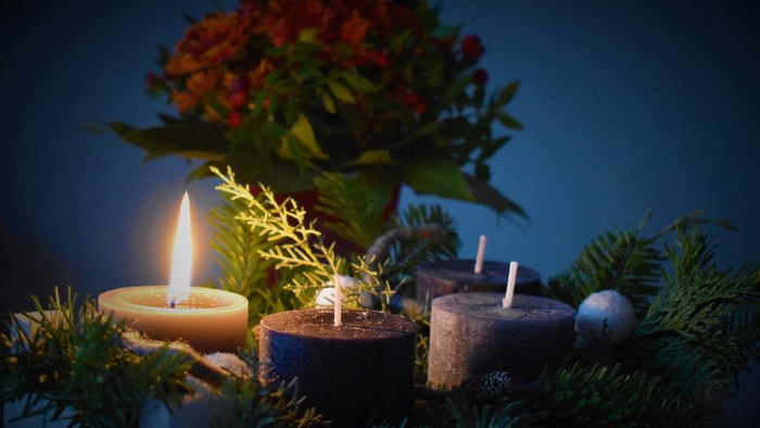 Dunkle Weihnachtsdekoration mit brennenden Kerzen und Blumen.