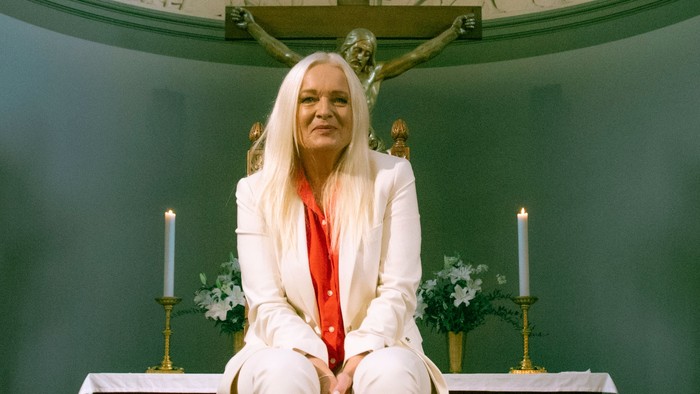 En kvinde i hvidt tøj sidder i en kirke.