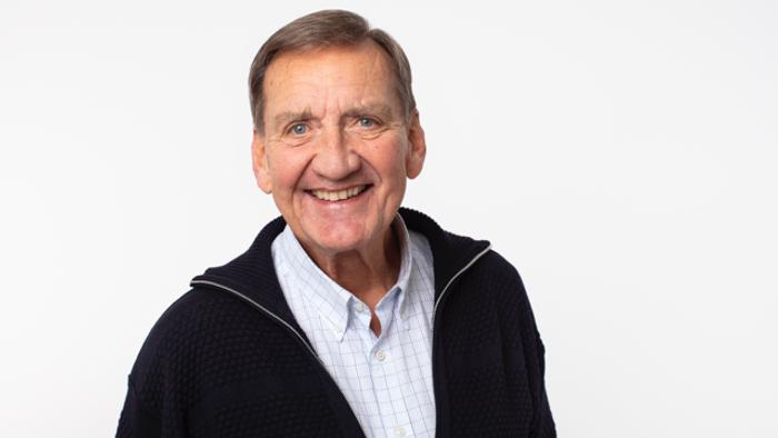 En glad og eldre mand med kort hår og en sort pullover.