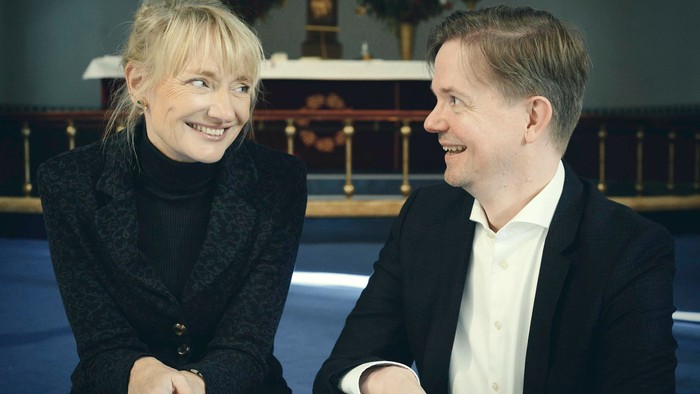 En mand og en kvinde står i en kirke og smiler til hinanden