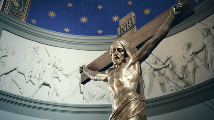 En statue af Jesus bærer korset i en kirke.
