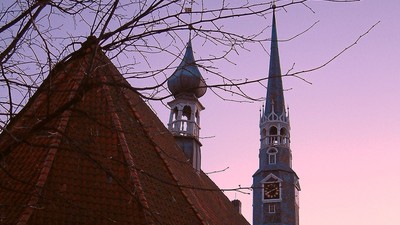 Weißes Kirchgebäude mit spitzen Turm vor lila Himmel