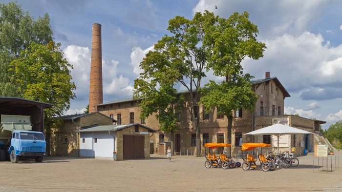 Altes Fabrikgebäude mit hohem Schornstein und Fahrrädern davor