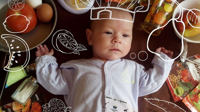 Baby i hvid køkkensmockey med køkkenudstyr og mad.