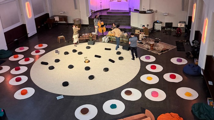 Bunte runde Sitzgelegenheit in einer geräumigen, gewölbten Kirche mit Musikinstrumenten und Darstellern.