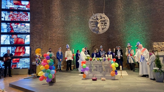 Eine Gruppe von Menschen feiert in einem Raum mit bunten Ballons und Dekorationen.