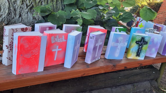 Mehrere Bücher mit Kreuzsymbolen auf Holzbank im Freien