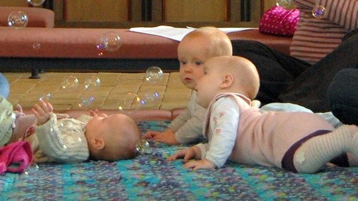 To børn ligger på gulvmat og spiller med boblene