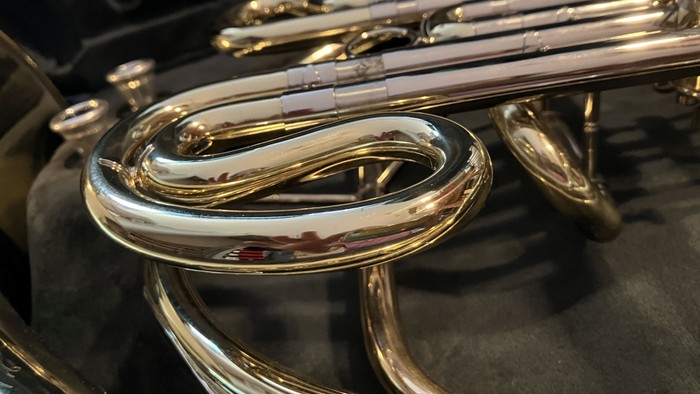 Ein poliertes Saxophon liegt auf einem dunklen Stoff.