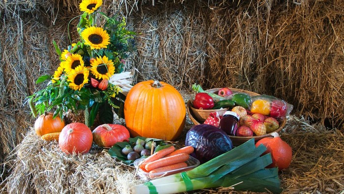 Ein Erntearrangement aus Gemüse und Blumen auf einem Heuboden