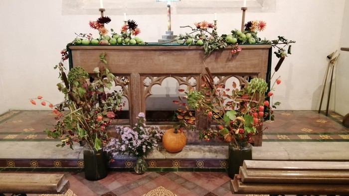 Altar decorated with flowers, candles, and pumpkin.