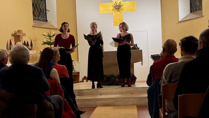 En kirke med tre kvinder på alteret og en forsamling af mennesker.