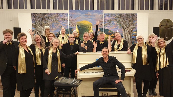 En gruppe sangere poser med piano i en kirke.