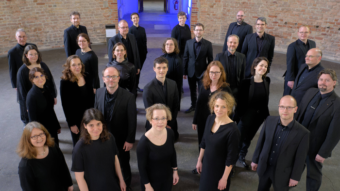 Ein Chor steht vor einer Ziegelmauer