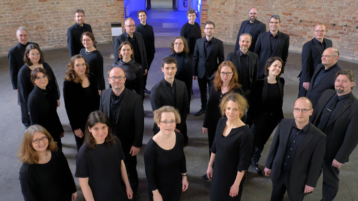 Ein Chor steht vor einer Ziegelmauer