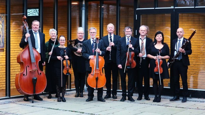 Et strygekvartet og orkesterets medlemmer poser sammen med forskellige instrumenter udendørs.