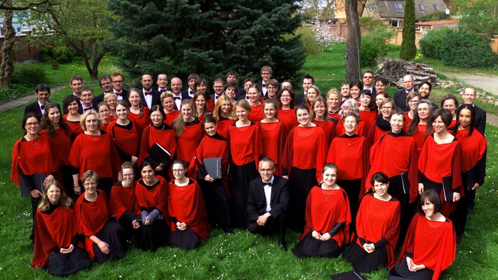 Große Gruppe von Menschen in roten und schwarzen Kleidern posiert im Freien