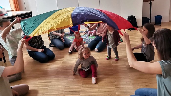 Kinder spielen mit einem bunten Regenschirm in einem Raum