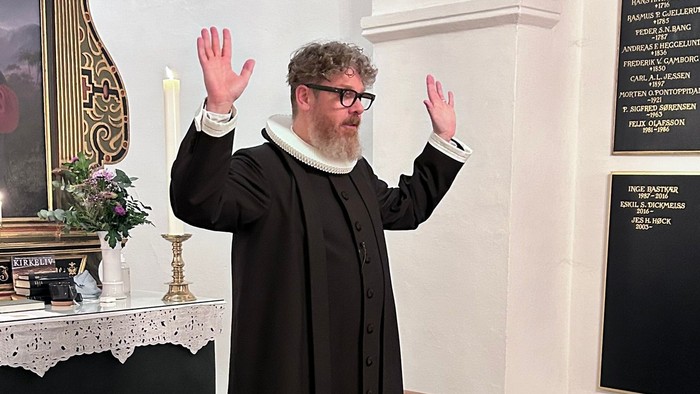 Mand i svart kapittel i kirke.