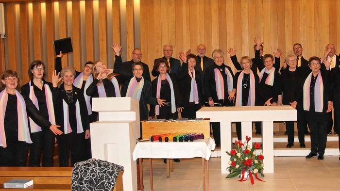 Ein Chor tritt in einer Kirche auf und hebt die Hände während eines Musik- oder Gottesdienstes.