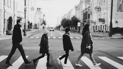 Vier Personen überqueren eine Zebrastreife in einer Stadt.