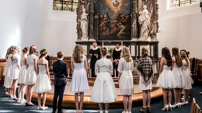 En gruppe børn i hvide kler ud over for alteret i en kirke